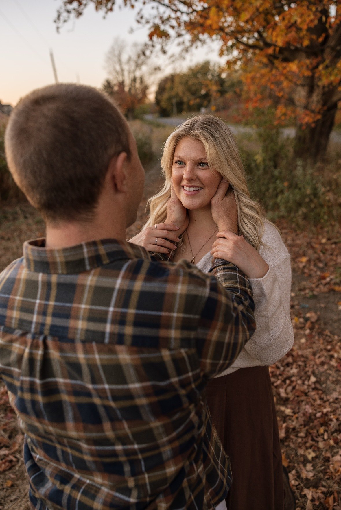 Couple close together surrounded by autumn foliage
