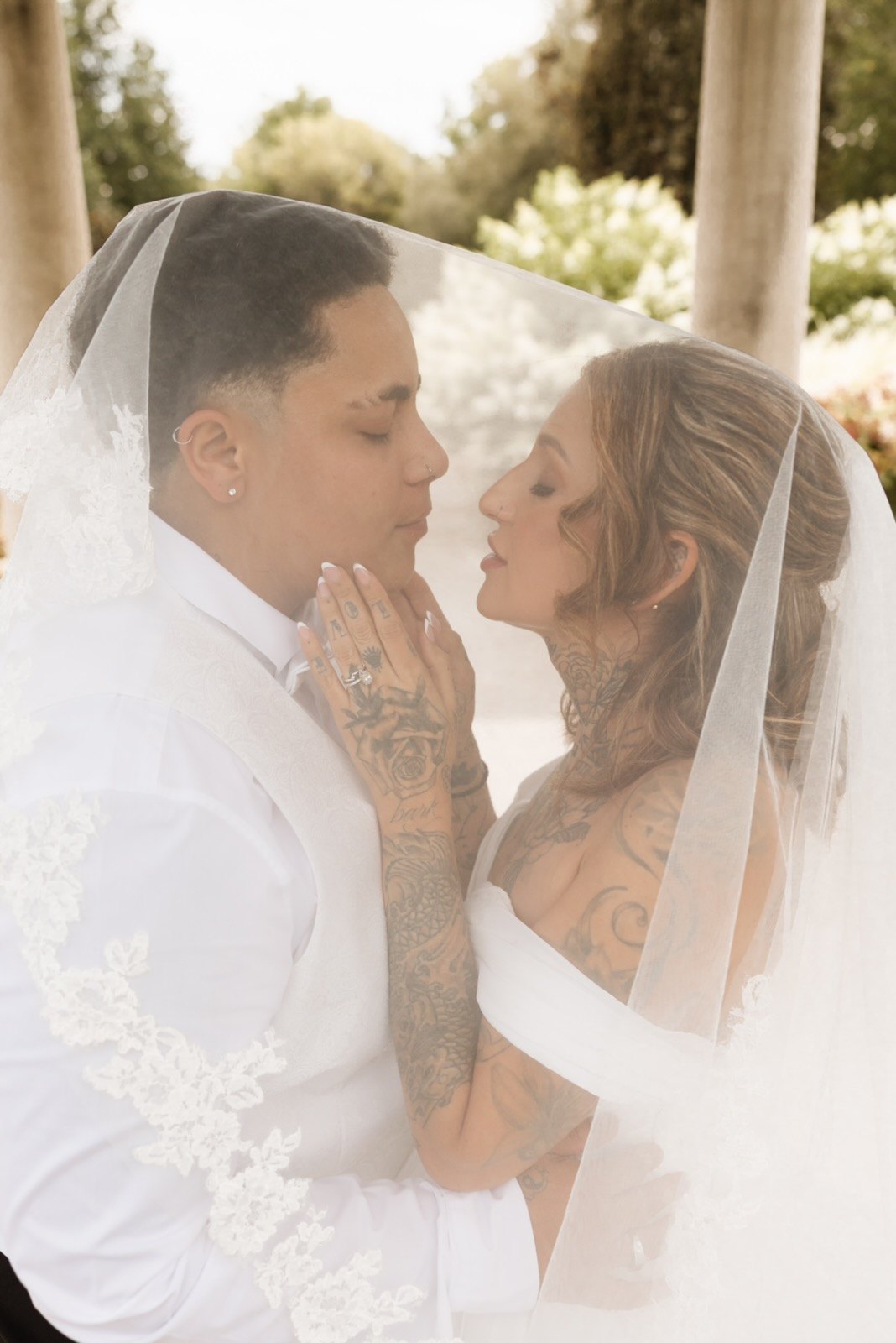 Groom holding the bride's face beneath her veil, an intimate garden portrait